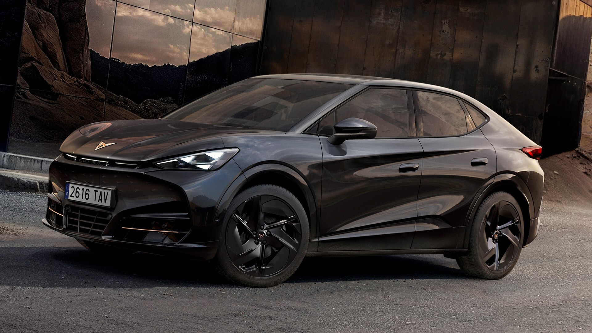 Hero angle, 3/4 front view of the CUPRA Tavascan Black Edition, parked in a rocky setting and showcasing its exterior details, such as the Katla 21-inch alloy wheels in black.